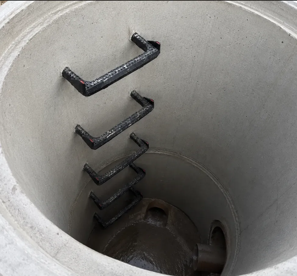 Black access steps installed inside a concrete manhole